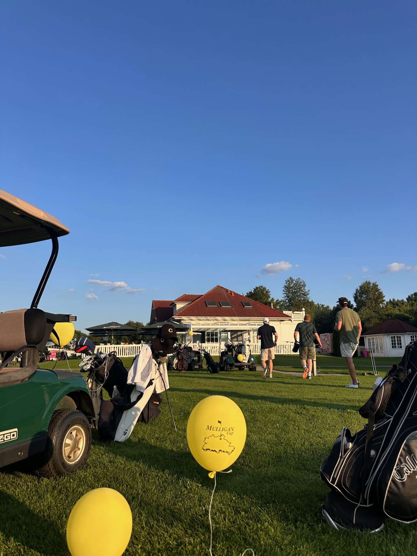 Clubhaus-Szene mit Golfcarts und Mulligan-Cup-Ballons